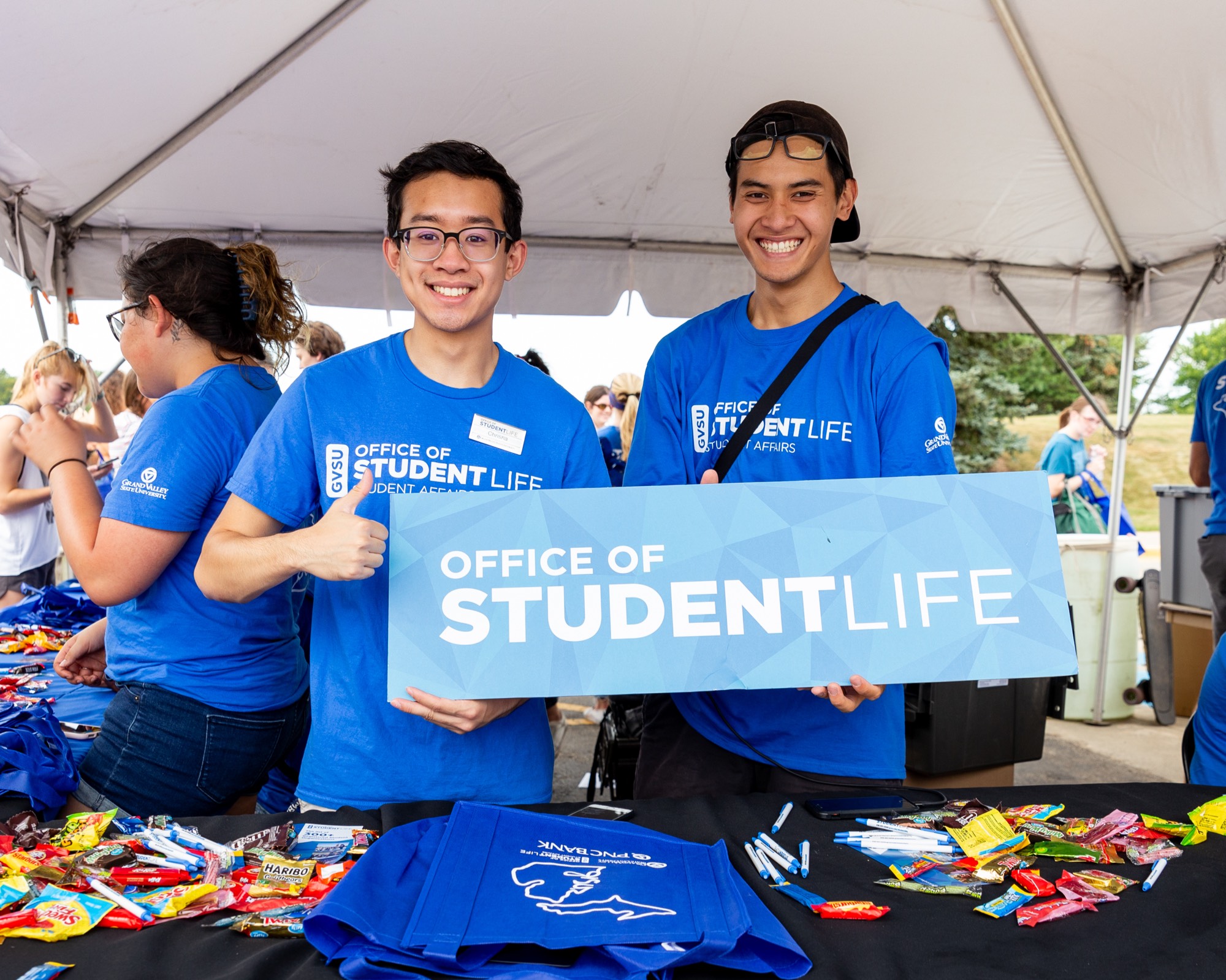 two students pose with a office of student life sign